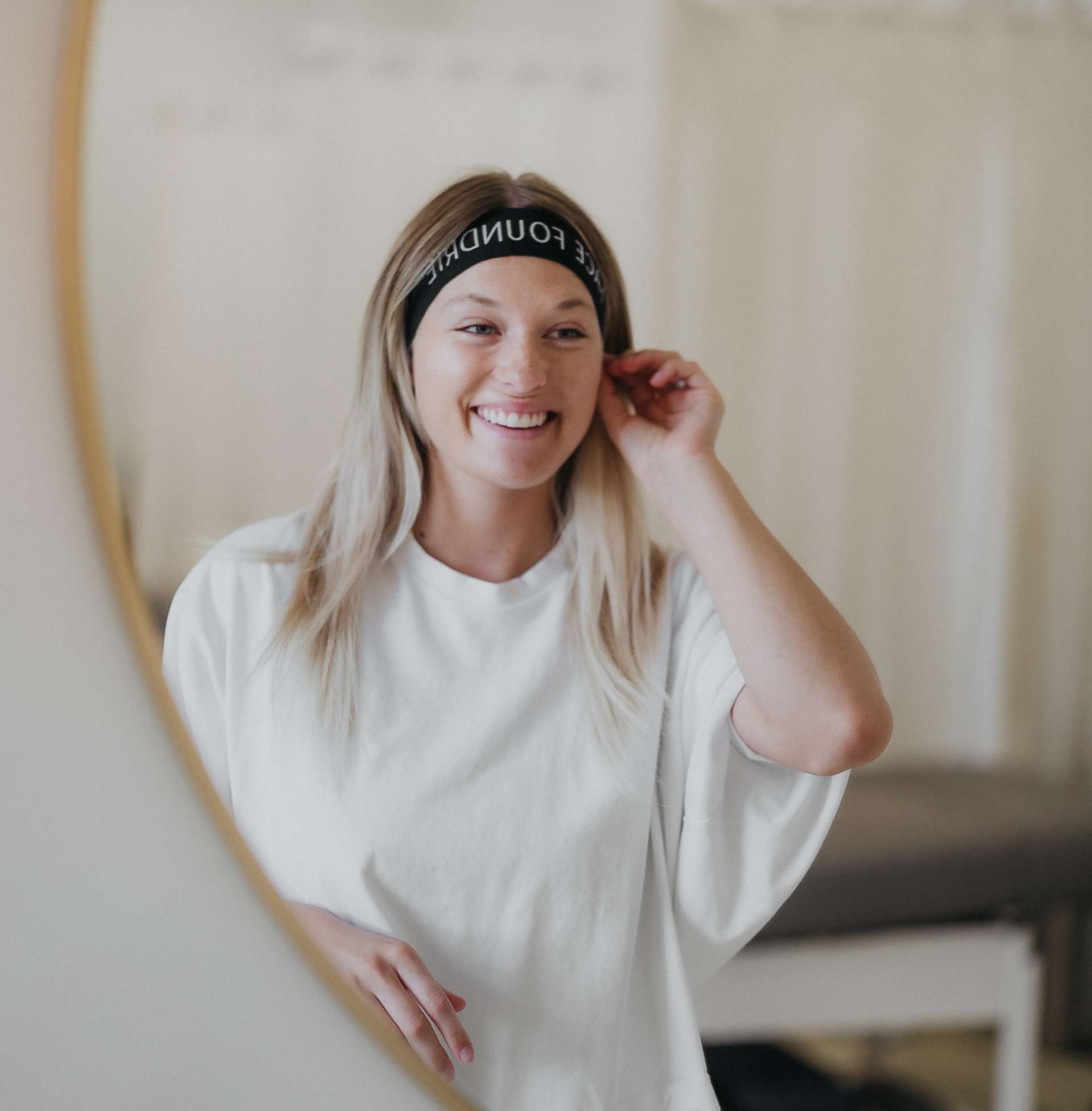 young woman smiling at herself in a mirror