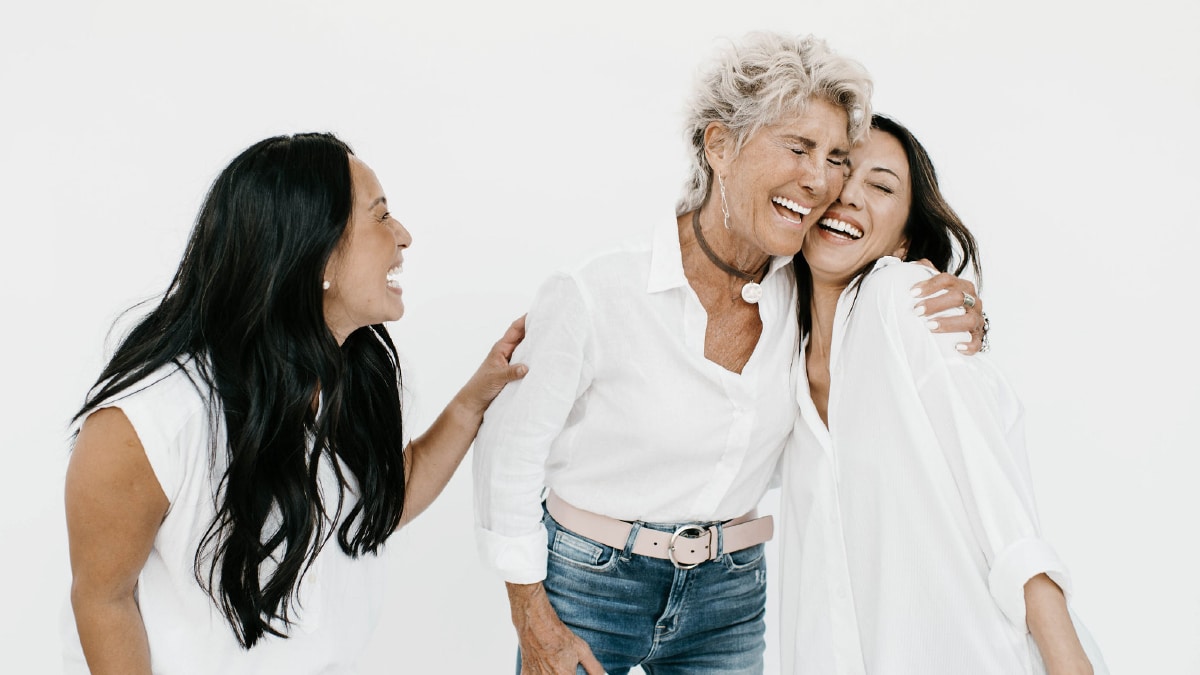 3 woman laugh and embrace each other.